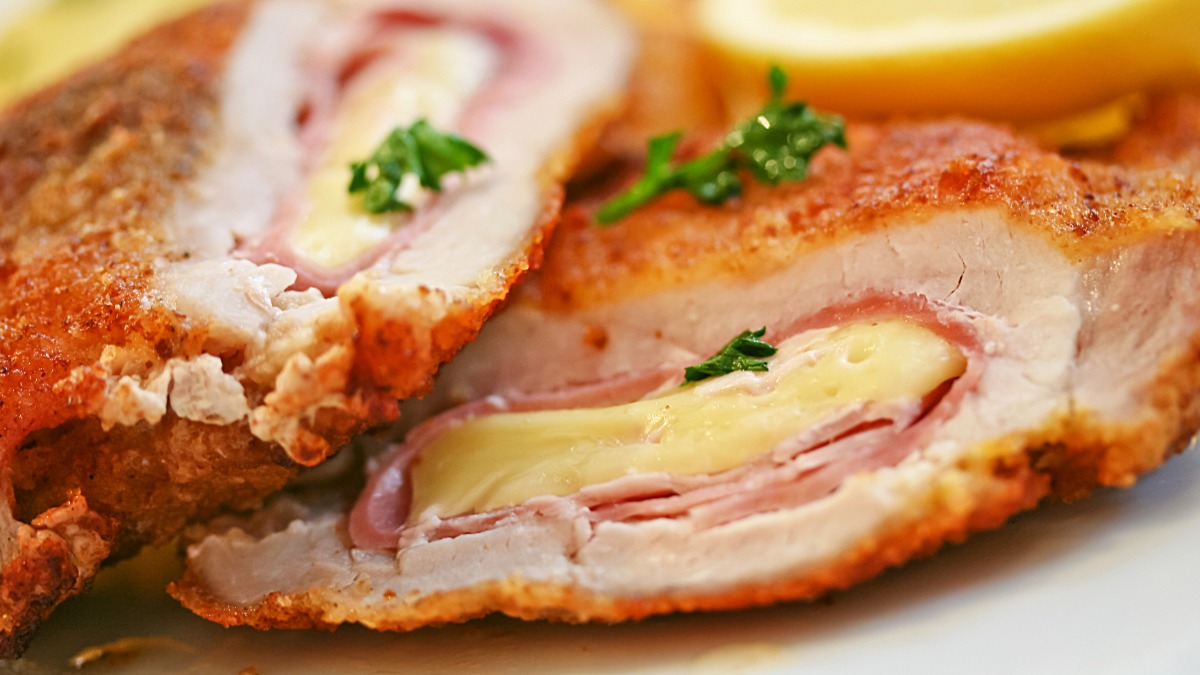 Knuspriges Cordon Bleu aufgeschnitten mit Schinken und Käse Füllung, garniert mit Petersilie und Zitronenscheibe